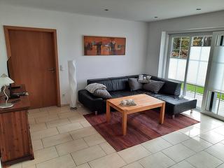 helles Wohnzimmer mit Sofa und Blick in den Garten